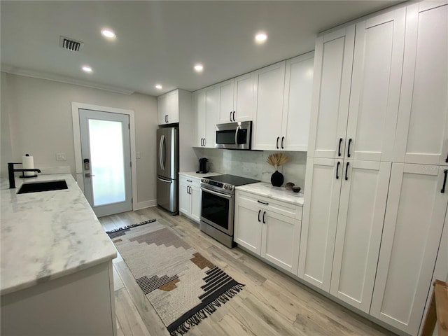 kitchen featuring stainless steel appliances, white cabinetry, light hardwood / wood-style floors, and light stone counters