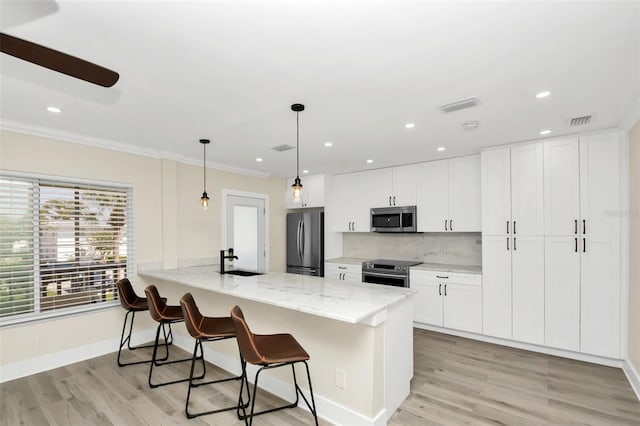 kitchen featuring pendant lighting, sink, light stone counters, white cabinetry, and stainless steel appliances