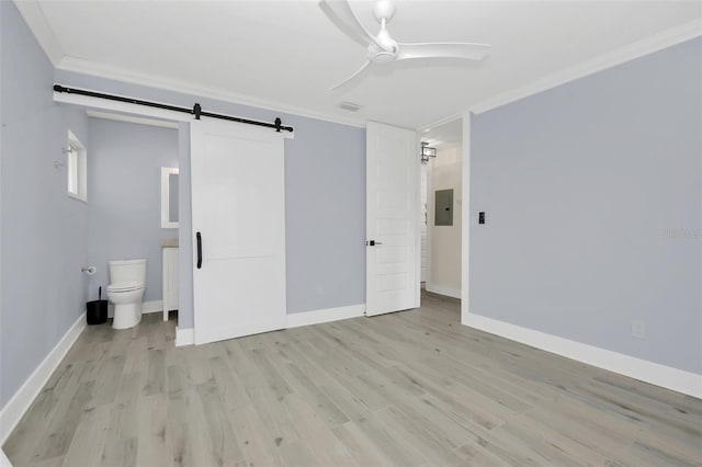 unfurnished bedroom with a barn door, light hardwood / wood-style floors, ensuite bath, and ceiling fan