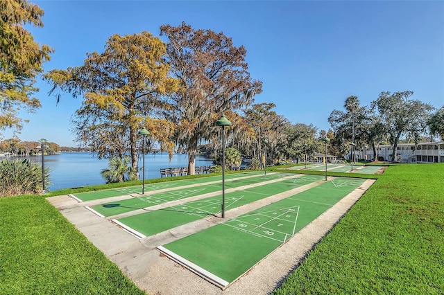 view of property's community with a water view and a lawn