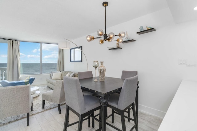 dining area with a chandelier, a water view, and light wood-type flooring