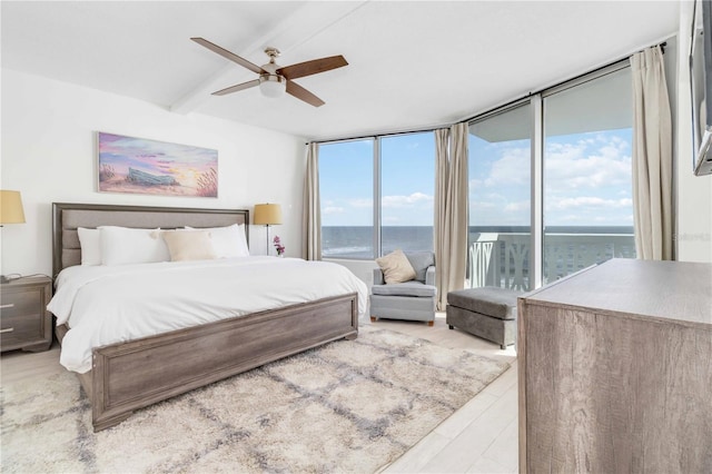 bedroom featuring light hardwood / wood-style flooring, multiple windows, and a water view