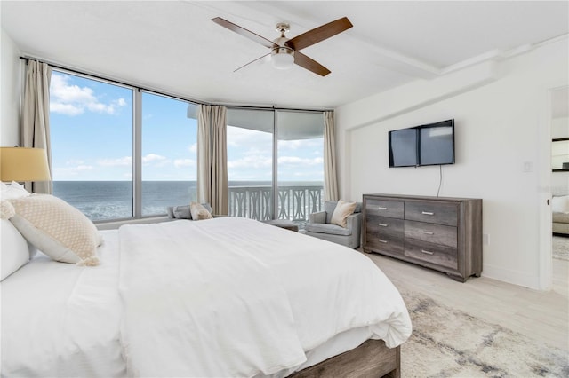 bedroom with access to outside, ceiling fan, light wood-type flooring, a water view, and floor to ceiling windows