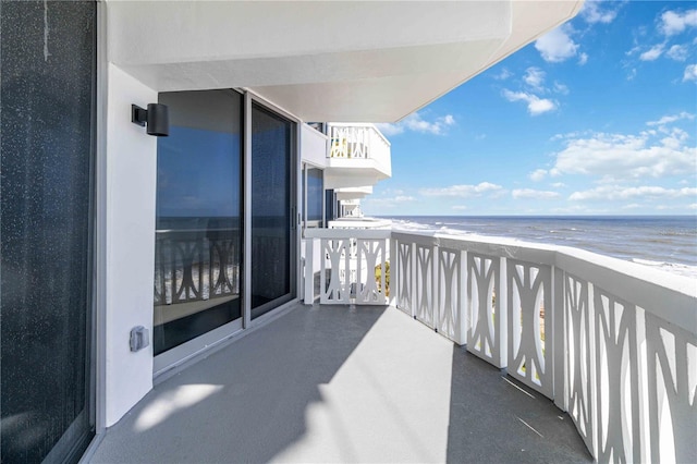 balcony featuring a view of the beach and a water view