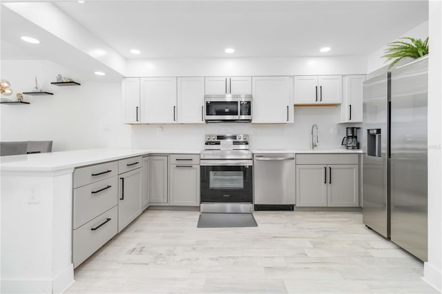 kitchen with light hardwood / wood-style flooring, kitchen peninsula, sink, appliances with stainless steel finishes, and tasteful backsplash