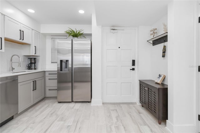 kitchen with light hardwood / wood-style floors, stainless steel appliances, sink, and gray cabinets