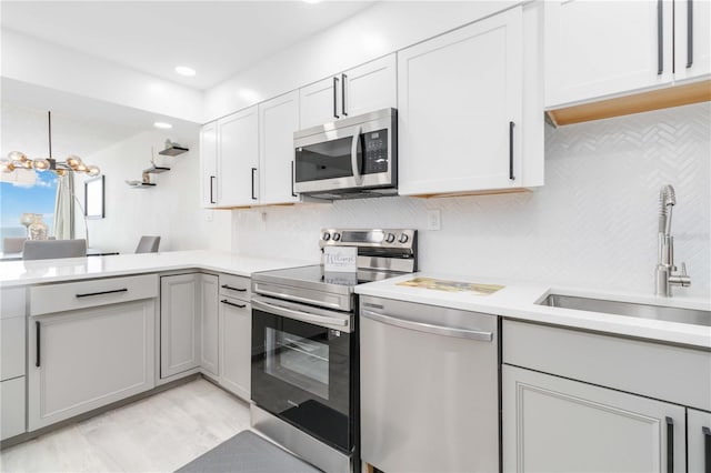 kitchen featuring sink, appliances with stainless steel finishes, a chandelier, and white cabinets