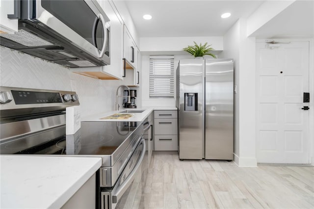 kitchen with light hardwood / wood-style floors, white cabinets, stainless steel appliances, and sink