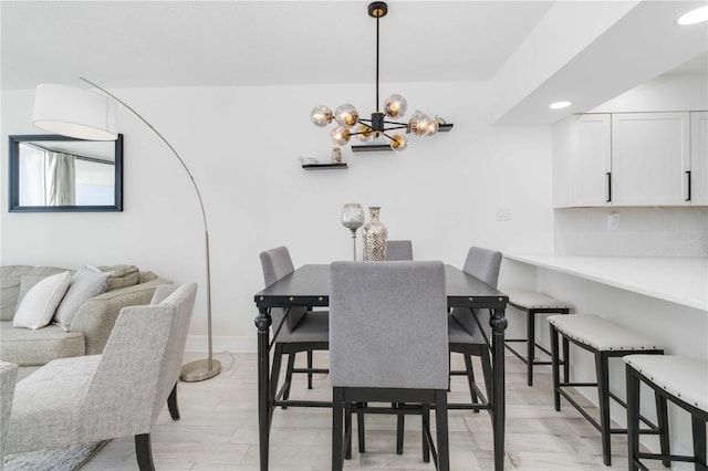 dining space with light hardwood / wood-style floors and a notable chandelier