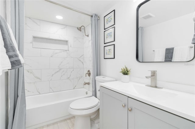 full bathroom with tiled shower / bath, vanity, and toilet