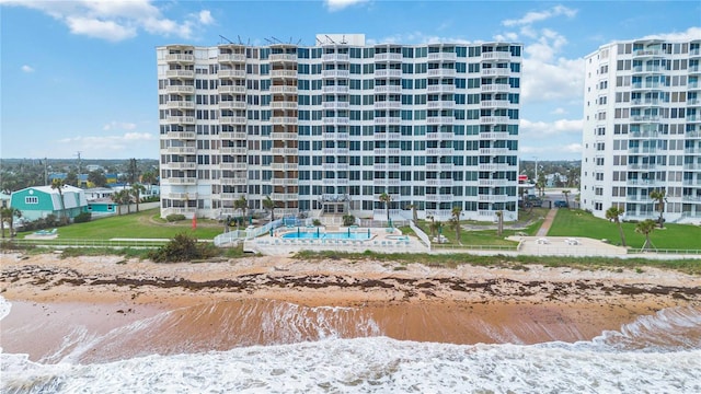 view of property featuring a water view, a community pool, and a beach view