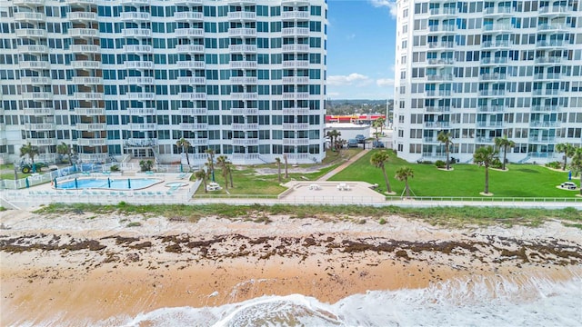 view of property featuring a community pool, a water view, and a beach view