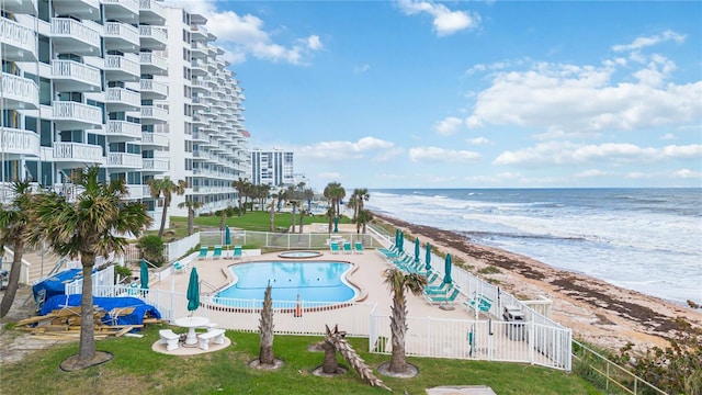 view of pool featuring a water view and a beach view