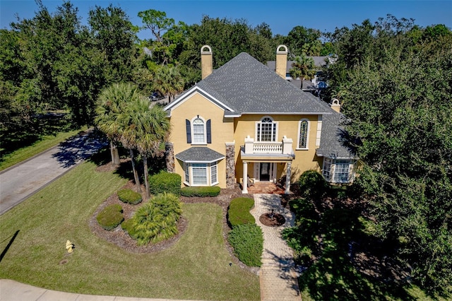 view of front of property featuring cooling unit, a front lawn, and a balcony