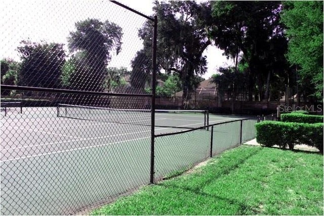 view of tennis court featuring a lawn