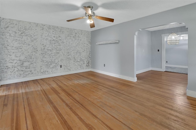 empty room featuring hardwood / wood-style floors, a textured ceiling, and ceiling fan with notable chandelier