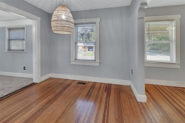 unfurnished dining area with a healthy amount of sunlight, a notable chandelier, and hardwood / wood-style floors