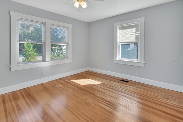 unfurnished room with ceiling fan, a wealth of natural light, and hardwood / wood-style floors