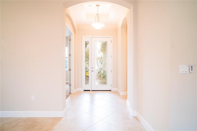 doorway featuring a tray ceiling and light tile patterned floors