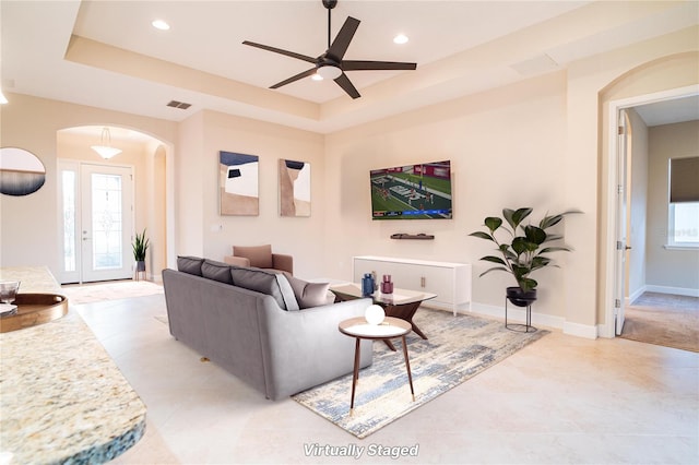 living room with ceiling fan and a raised ceiling