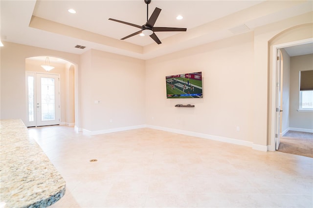 spare room with french doors, a tray ceiling, and ceiling fan