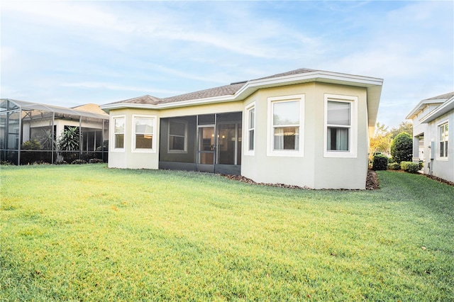 rear view of house featuring a yard and a sunroom