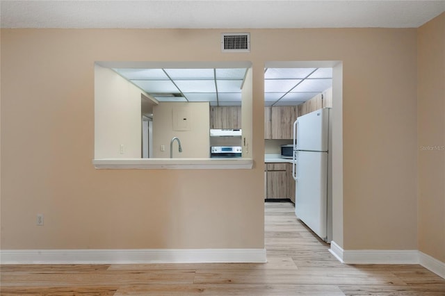 kitchen with light hardwood / wood-style floors, white fridge, stove, and sink