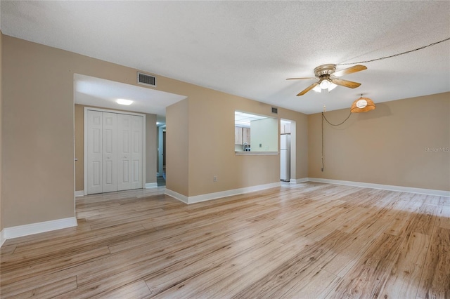 spare room with light hardwood / wood-style floors, a textured ceiling, and ceiling fan