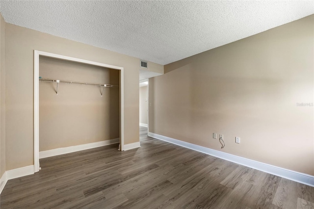 unfurnished bedroom featuring dark wood-type flooring, a closet, and a textured ceiling