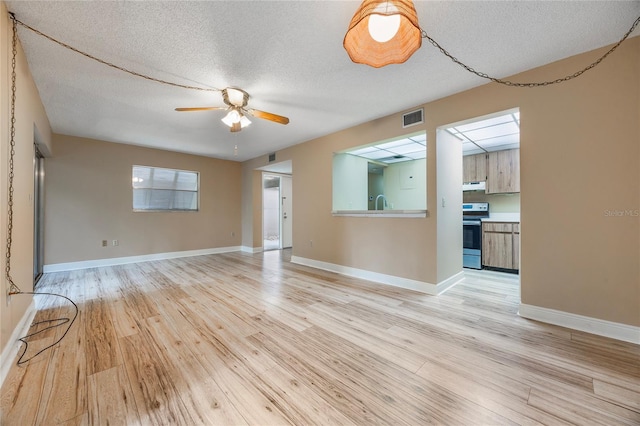 unfurnished room with ceiling fan, a textured ceiling, and light wood-type flooring