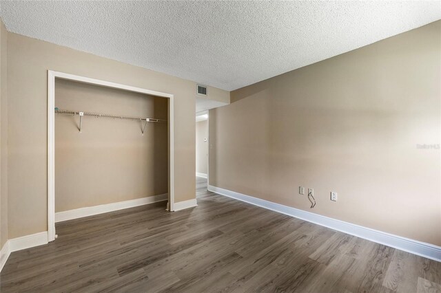 unfurnished bedroom with dark wood-type flooring, a textured ceiling, and a closet