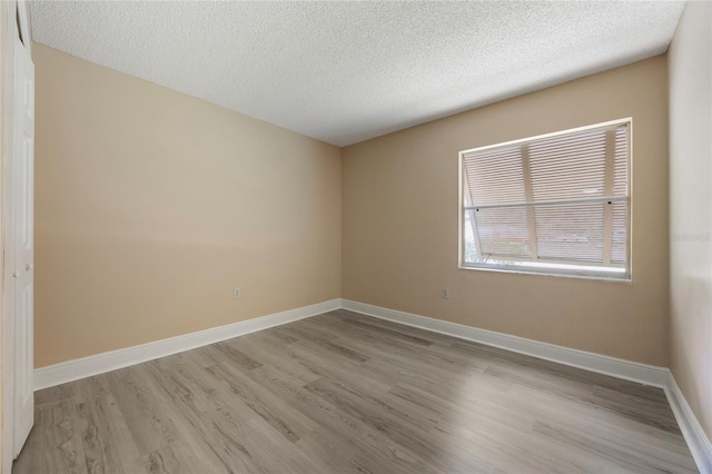 spare room with a textured ceiling and light hardwood / wood-style flooring