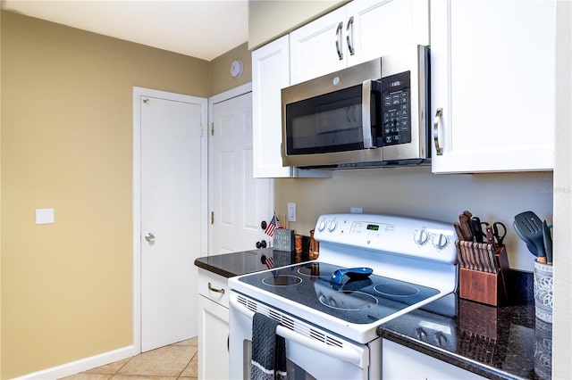 kitchen featuring white cabinets, dark stone countertops, white electric range oven, and light tile patterned floors