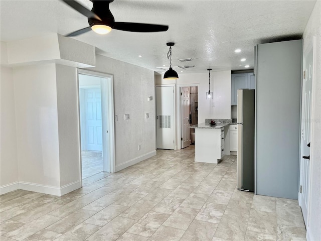 kitchen with hanging light fixtures, a center island, gray cabinets, a textured ceiling, and ceiling fan