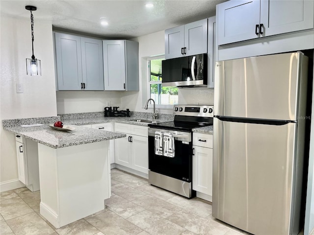 kitchen featuring stainless steel appliances, sink, decorative light fixtures, light stone counters, and a textured ceiling