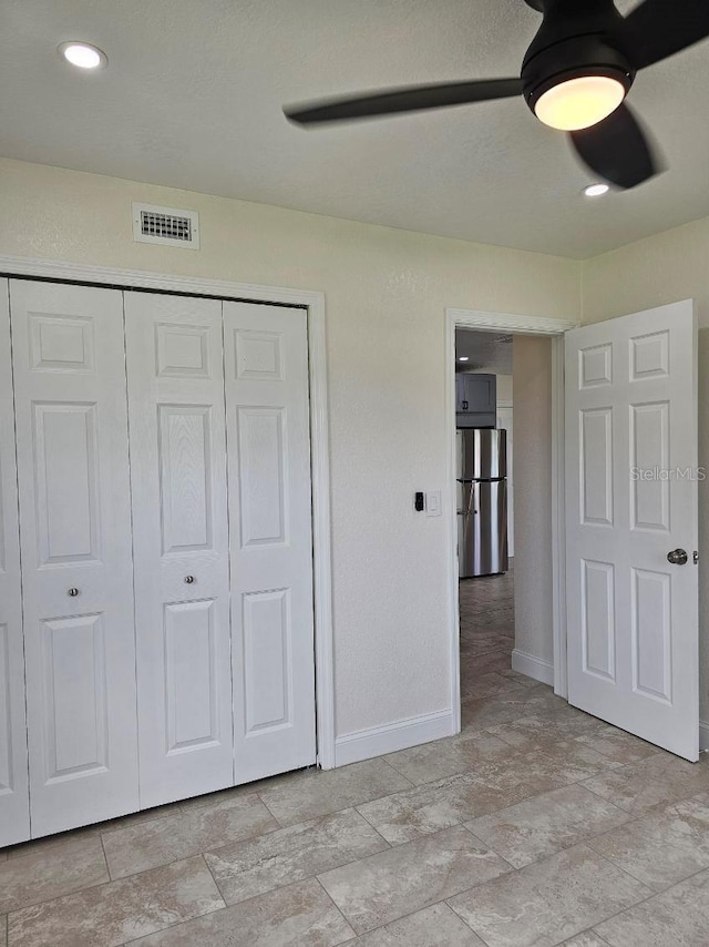 unfurnished bedroom featuring a closet, ceiling fan, and stainless steel refrigerator