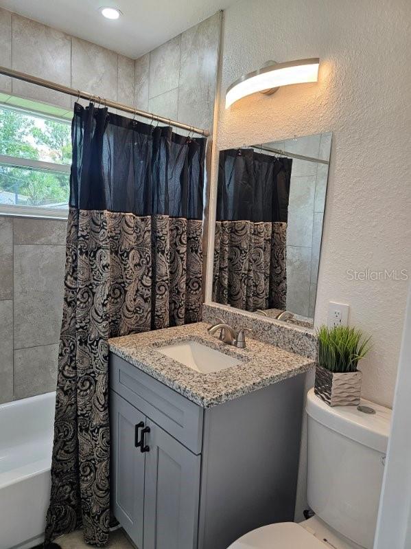 full bathroom featuring vanity, shower / tub combo, and toilet