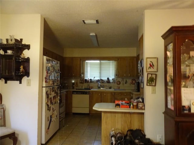 kitchen with decorative backsplash, tile patterned flooring, kitchen peninsula, a textured ceiling, and white appliances