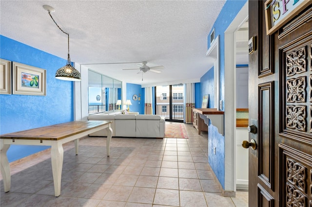 dining area with ceiling fan, floor to ceiling windows, light tile patterned floors, and a textured ceiling