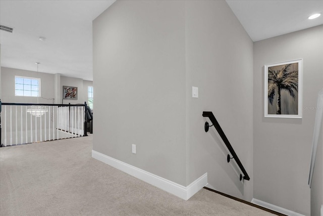 stairway with a notable chandelier and carpet