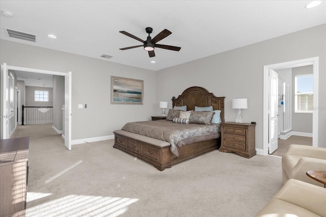 carpeted bedroom with ceiling fan, multiple windows, and ensuite bathroom