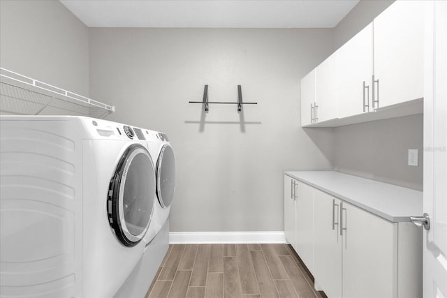 laundry room with separate washer and dryer, cabinets, and light wood-type flooring