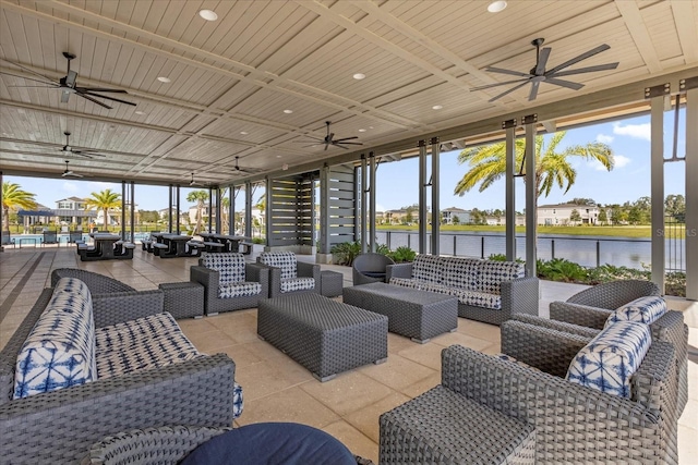 view of patio with a water view, ceiling fan, and an outdoor living space