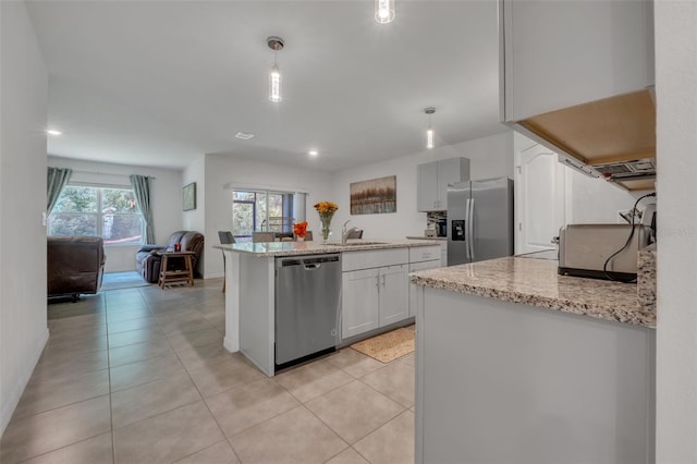 kitchen with light stone countertops, white cabinetry, sink, pendant lighting, and appliances with stainless steel finishes