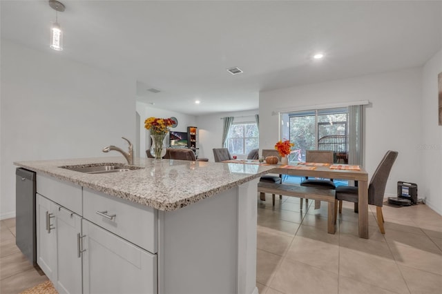 kitchen featuring sink, light stone countertops, an island with sink, decorative light fixtures, and white cabinetry