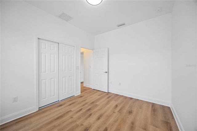 unfurnished bedroom with light wood-type flooring and a closet