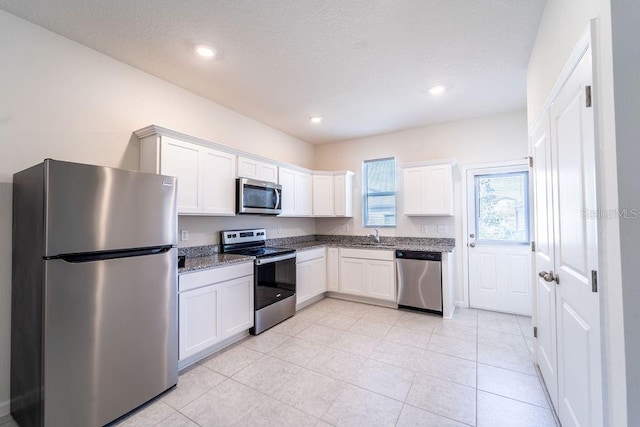 kitchen featuring white cabinetry, stainless steel appliances, sink, and stone countertops