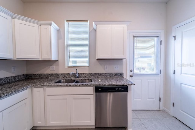 kitchen featuring dishwasher, dark stone countertops, sink, light tile patterned floors, and white cabinetry