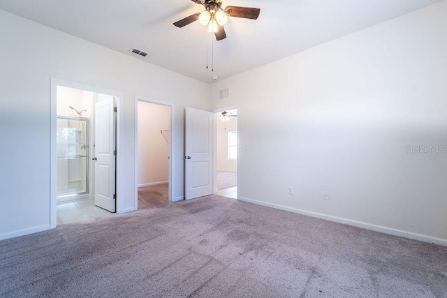 unfurnished bedroom featuring connected bathroom, a walk in closet, a closet, and ceiling fan