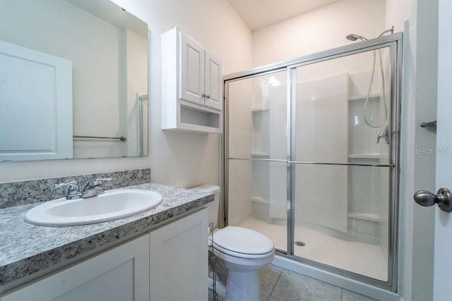 bathroom with vanity, a shower with shower door, toilet, and tile patterned floors